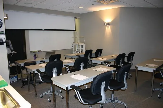 Classroom with table and chairs, view from the back, at Brodine Prosthodontic Seminars in Rochester, NY